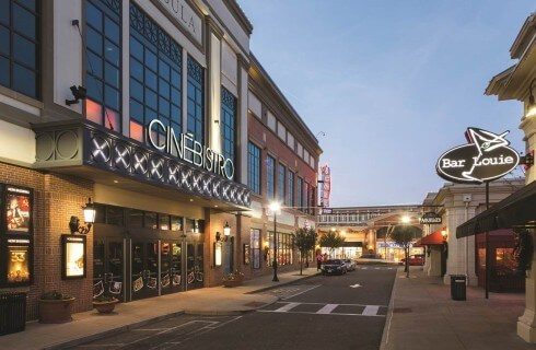 A downtown main street shopping and dining area with several glass front buildings with signs