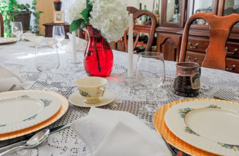 Dining table with lace tablecloth and fine china, gold charger plates and white linens