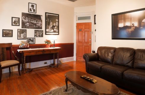 Sitting area of a guest room with a side table and chair and leather sofa in front a coffee table