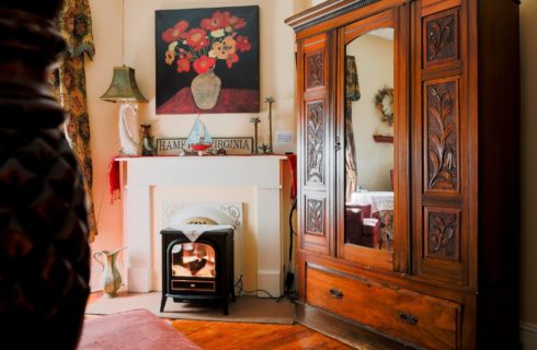 Vintage fireplace with electric firebox next to a large brown armoire with mirrored front