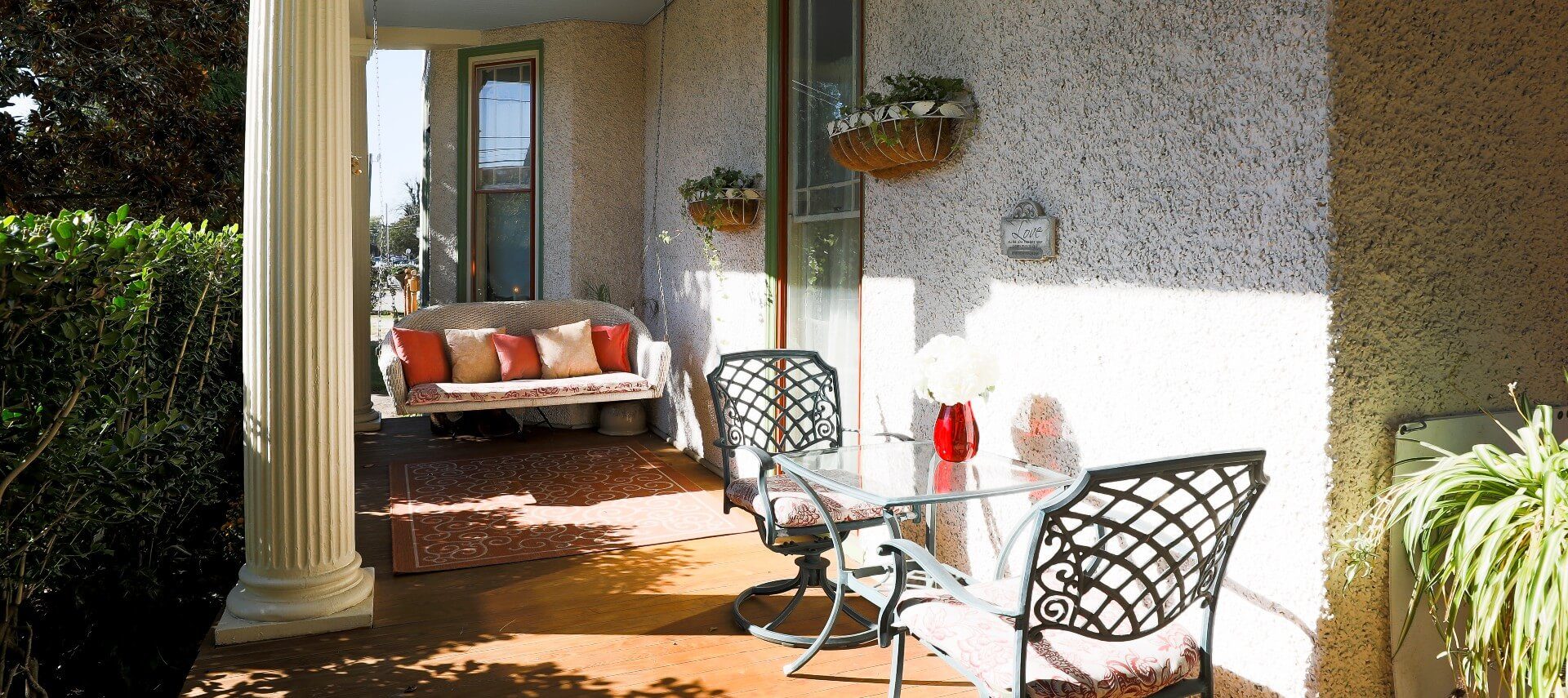 Outside patio of a home with hanging loveseat and wrought iron table with two chairs